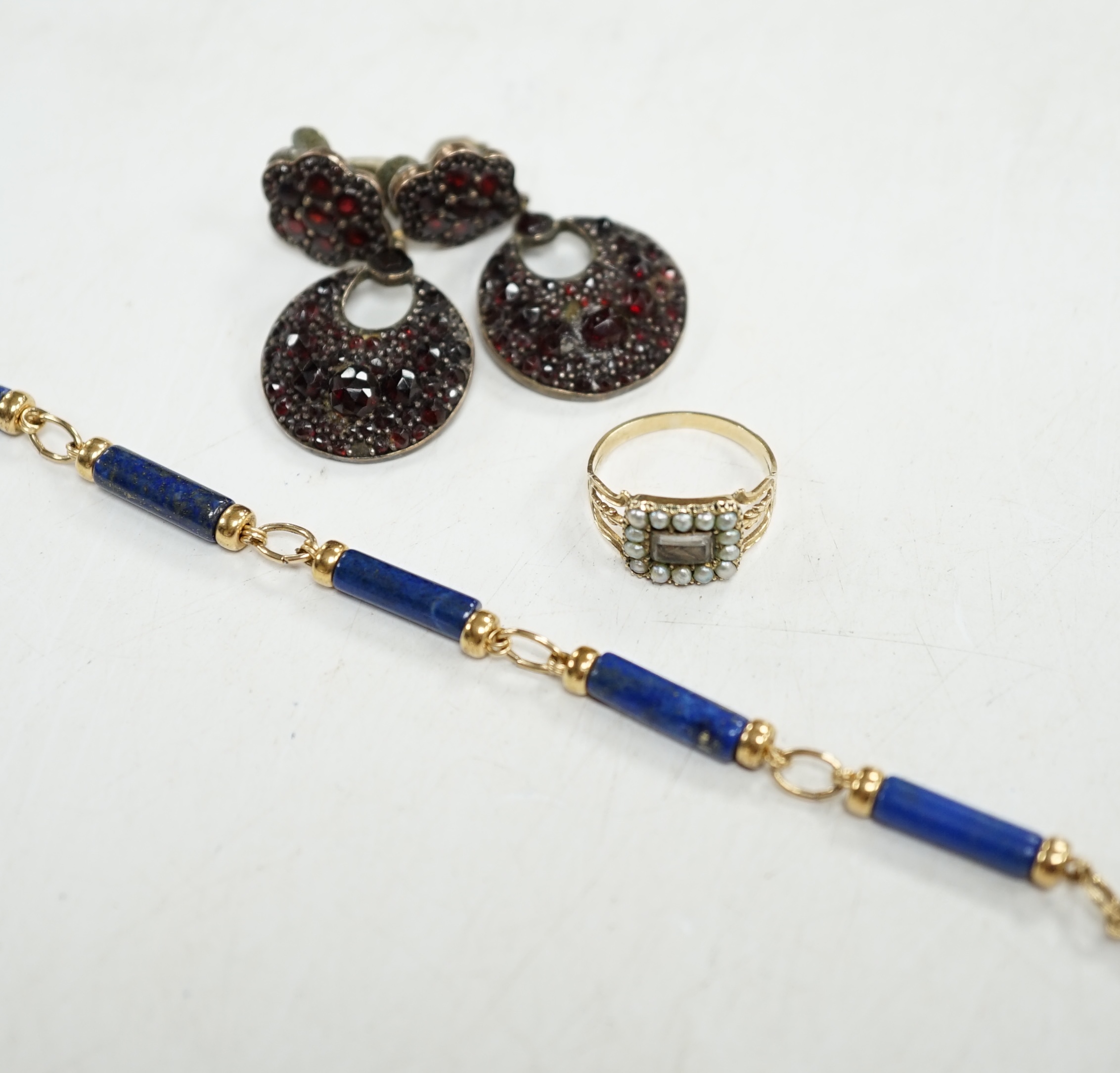 A Victorian gold and split pearl mourning ring, with central hairwork plaque, size I, 1.7 grams, a yellow metal mounted lapis lazuli baton bracelet and a pair of garnet set base metal drop earrings. Condition - fair